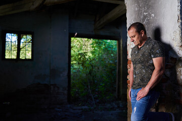 Naklejka premium Mature man in a ruined barn and house
