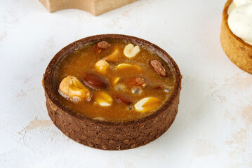 Mini chocolate cakes on wooden background. Cashew nut filling, almonds, peanuts.