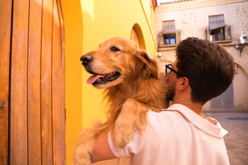 handsome young Hispanic man with his brown golden retriever dog. The man holds the dog in his arms. Concept pets, animals, dogs, pet love, golden retriever.