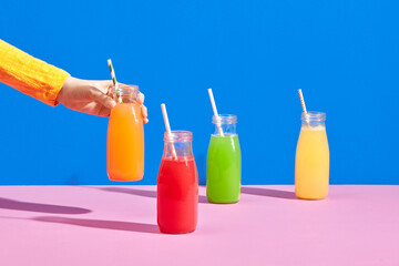 Hand holding the bottle of orange color cold pressed fruit