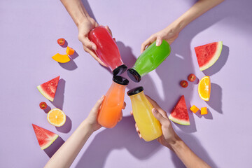 Flat-lay of human hands holding fresh juices in bottles