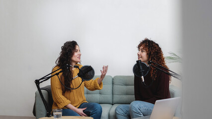 Female host recording radio podcast interview with guest at home office - Main focus on right latin woman face