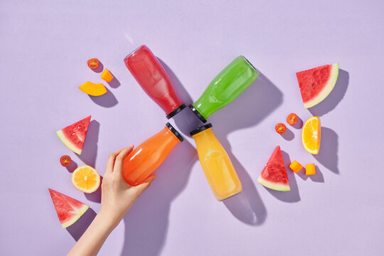 Female hand with bottles of tasty orange, watermelon