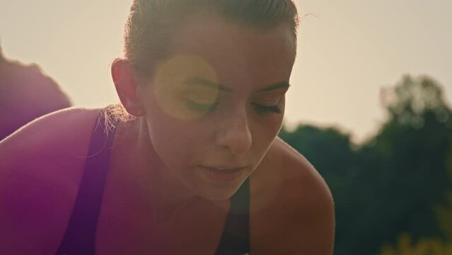 Motivated young woman runner caucasian female jogger sit in bent position on start line ready to jog race track marathon preparing for sprint run practicing sports training speed outdoors at sunrise