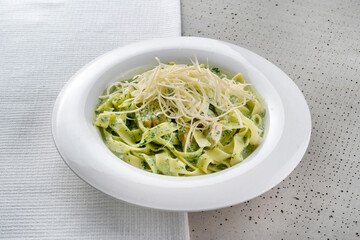 Spaghetti with cheese and herbs. On a white plate, black background. Symmetrical composition