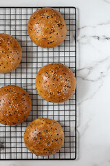 Top view of burger buns decorated white and black sesame on a cooling rack