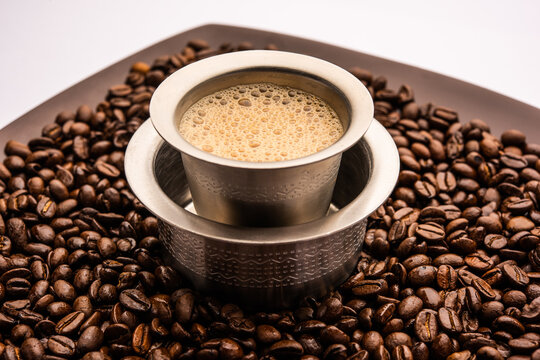 South Indian Filter coffee served in a traditional tumbler or cup over roasted raw beans © StockImageFactory