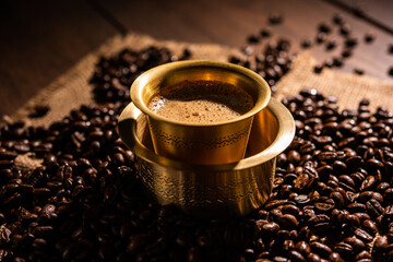 South Indian Filter coffee served in a traditional tumbler or cup over roasted raw beans