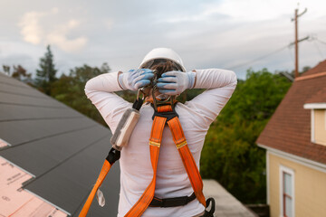 Female builder roofer putting on safety gear