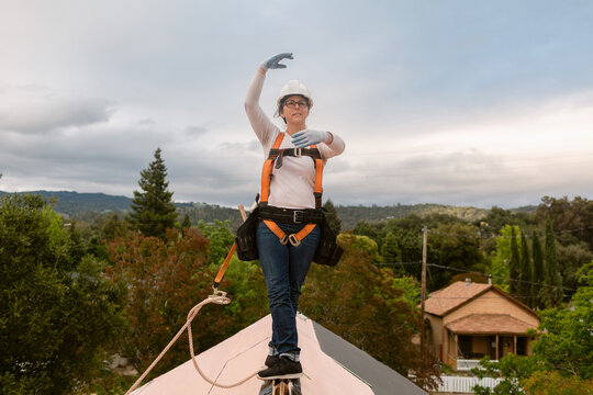 Roofer woman on top of solar roof balancing