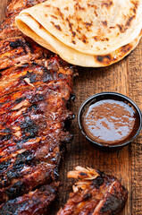 piece of baked meat, grilled beef pork ribs with sauce and bread on a wooden background