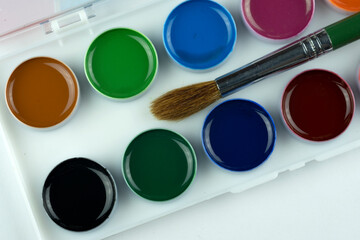 Watercolor paints and a brush for children's creativity, isolated on a white background.