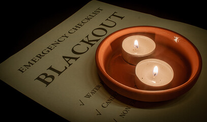 two tea lights in a terracotta coaster on a blackout emergency checklist during a power outage