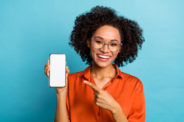 Portrait of attractive trendy cheery wavy-haired girl demonstrating gadget copy space isolated over...