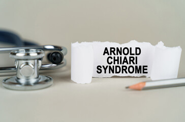On a gray background, a stethoscope, a pencil and a paper plate with the inscription - Arnold chiari syndrome - obrazy, fototapety, plakaty