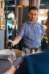 waiter brings a bottle of quality white wine for a couple, and serve it to the lady in her glass at the restaurant