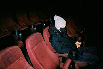 Young man in mask in cinema