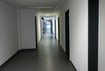 Weißer langer Flur mit Türen in Klinikgebäude 