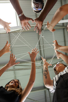 Crop coworkers joining hands with thread 