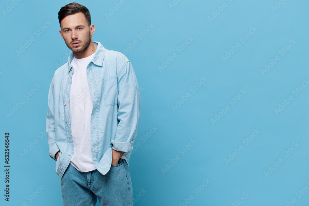 Wall mural Attractive beautiful confident tanned handsome man in casual basic t-shirt posing isolated on blue studio background. Copy space Banner Mockup. People emotions Lifestyle concept. Cool fashion offer