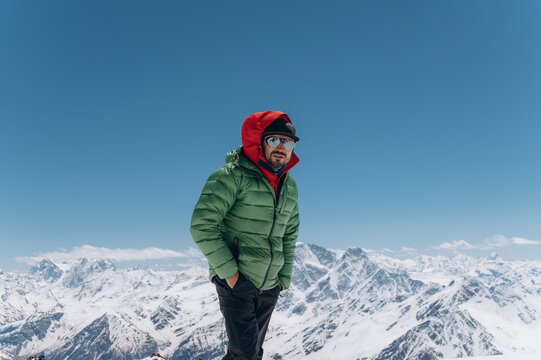 Male traveler standing on snowy mountain top in winter