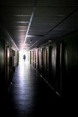 Woman walking alone in the dark. Woman, in a dark, long corridor, defocused