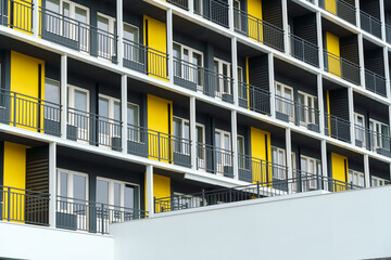 the facade of a modern multi-storey building, windows and balconies, yellow and black walls, the concept of urbanism and city construction