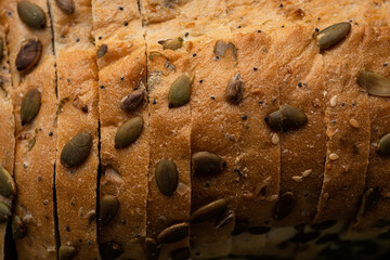 Close up detail of sliced white bread loaf seeded with pumpkin seeds, sunflower seeds, sesame seeds, poppy seeds