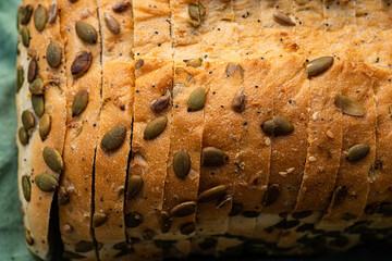 Close up detail of sliced white bread loaf seeded with pumpkin seeds, sunflower seeds, sesame seeds, poppy seeds - 532546583