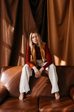 Stylish lady sitting on sofa back against curtains