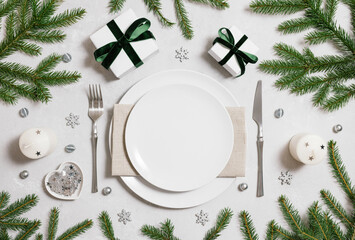 Christmas empty table setting with silver decor and fir branches on gray background. View from above. Space for text.