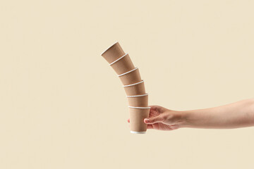 Tower of brown ribbed paper cups in female hand.