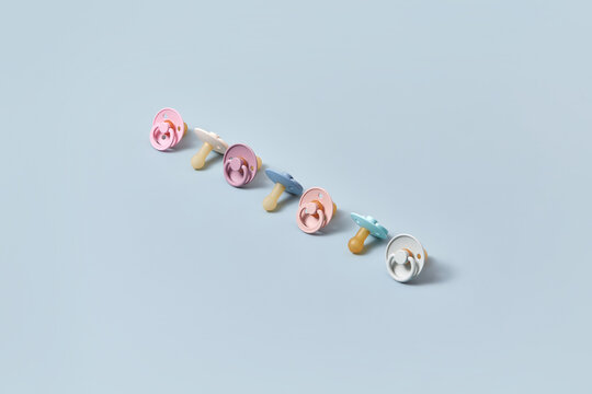 Row of colorful pacifiers on blue background.