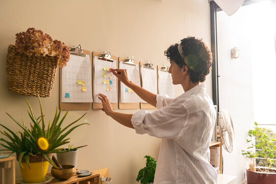 Mature businesswoman working with sticky notes on schedule plan 