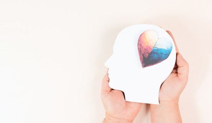 Holding a head with a colorful heart in the hands, symbol of love and positive emotion, charity and support