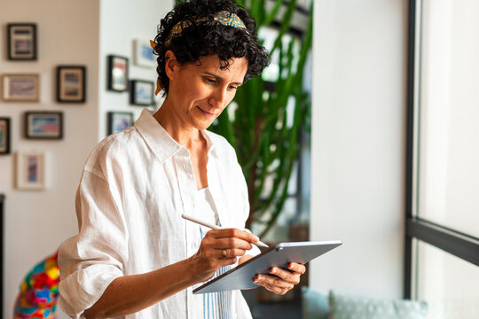 Mature woman using digital tablet at home office
