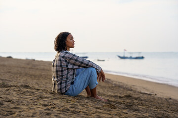 Naklejka premium Woman sitting alone watching ocean waves