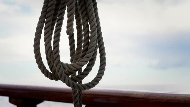 Close-up of the rope on the yacht swings in the wind and waves Old sailboat with wooden details in the open sea. Waves and sky in the background. Slow motion footage