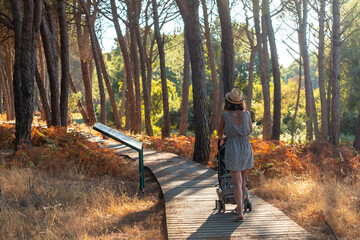 Wooden walkway with a mother with her son walking through the Doñana Natural Park, Huelva. Andalusia - obrazy, fototapety, plakaty