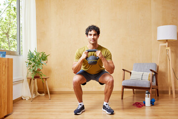 Positive Hispanic sportsman squatting with kettlebell