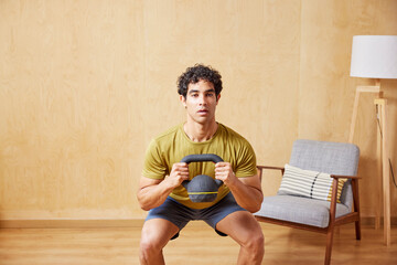 Tired athlete doing kettlebell goblet squats at home
