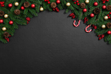 Christmas arch with fir branches, red and golden decor and candy cane on a black background. Happy...