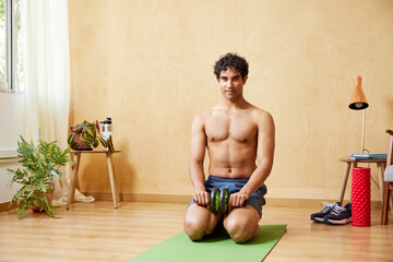 Shirtless Hispanic sportsman with ab roller