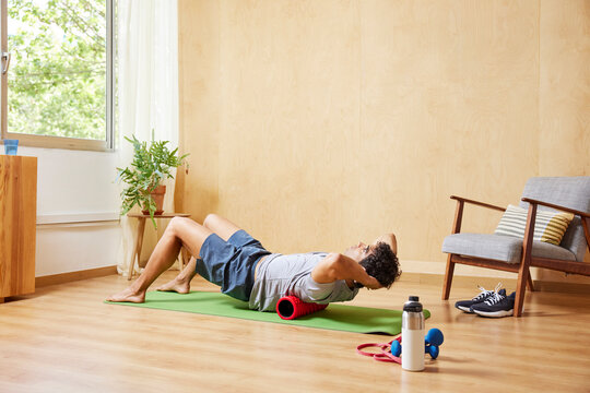 Man doing spinal alignment exercise with foam roller