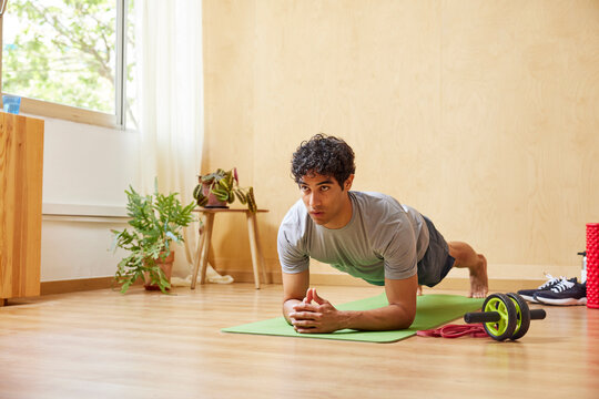 Hispanic male athlete doing elbow plank on floor
