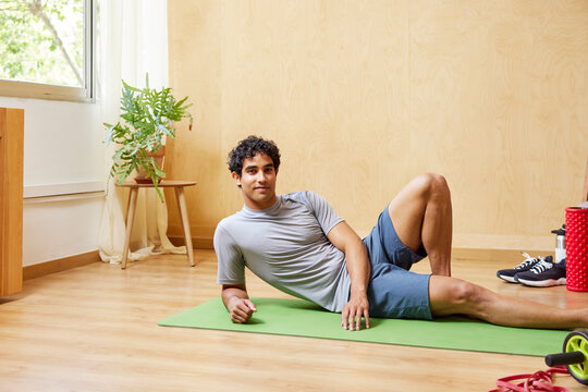 Content guy relaxing on mat after training at home