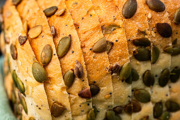 sliced white bread loaf encrusted with pumpkin seeds, sunflower seeds, sesame seeds, poppy seeds - 532551735