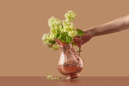 Vintage copper jug with flowers held by woman.