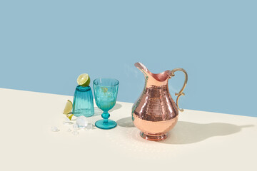Copper jug and glass of fresh lime drink and ice.