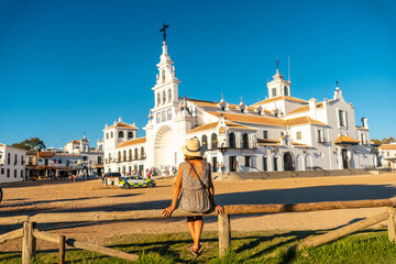 A young woman tourist sitting and looking at the Rocio sanctuary at the Rocio festival, Huelva. Andalusia